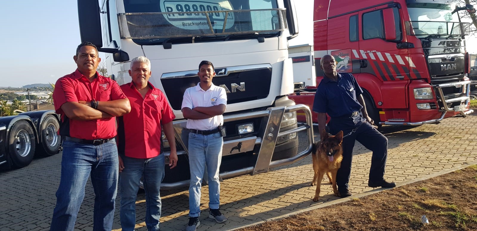 Redlight Security team standing with a trained dog in front of trucks