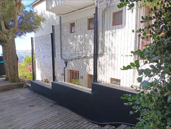 Black metal fence on a low concrete wall by a deck