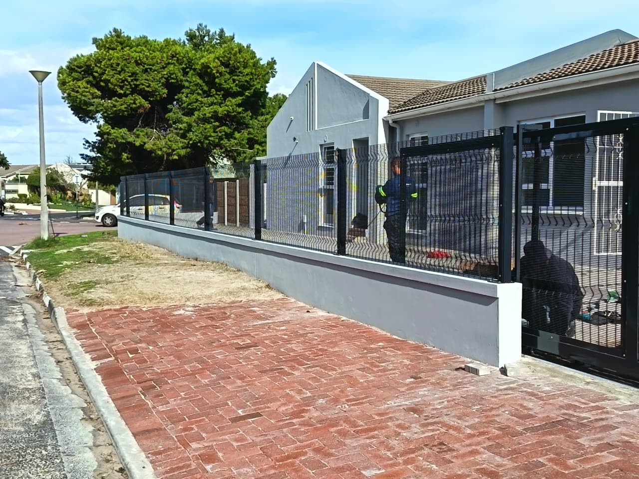 Newly installed black metal security fence on a grey wall