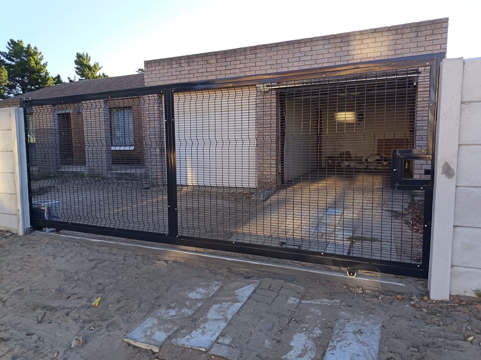 Black metal sliding gate with wire mesh infill